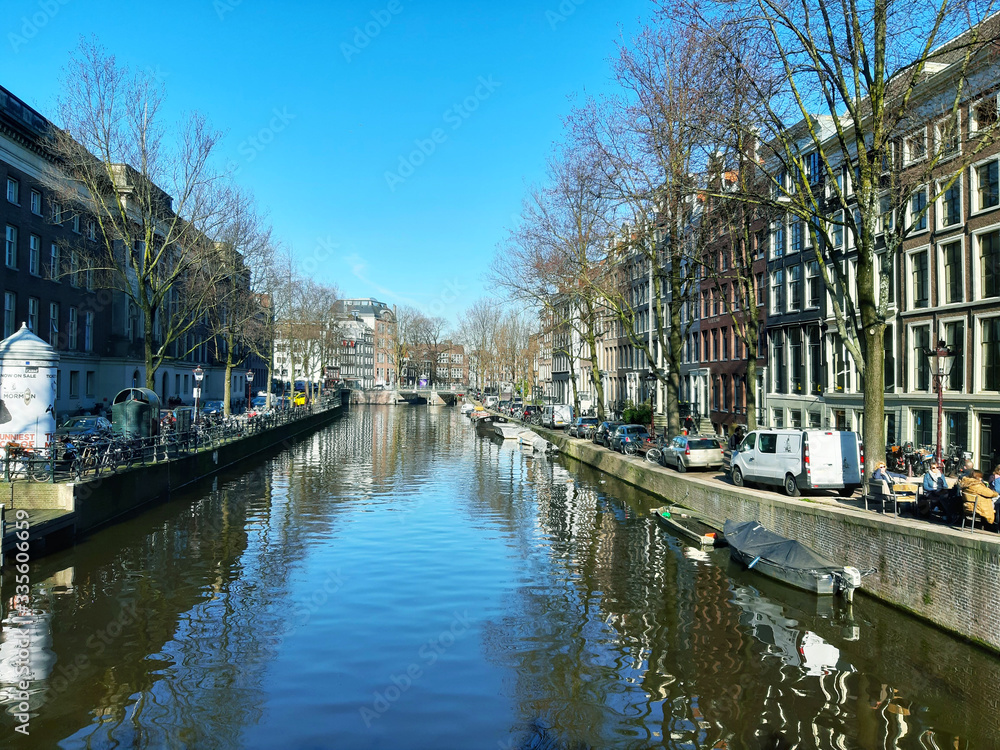 normal daily life in the canal waters of amsterdam between buildings in the sun