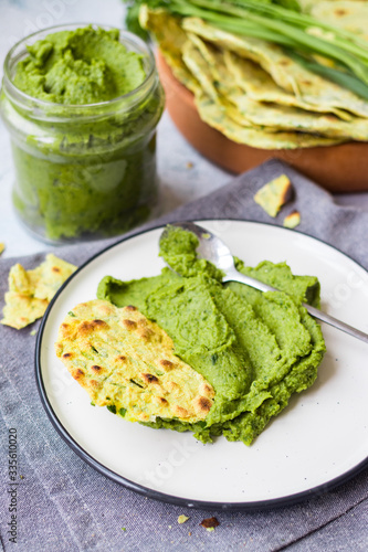 Green chickpea hummus with spinach and parsley in glass jar and flatbread tortillas, chapati or pita bread. Vegan lunch or vegetarian dinner. Healthy food.