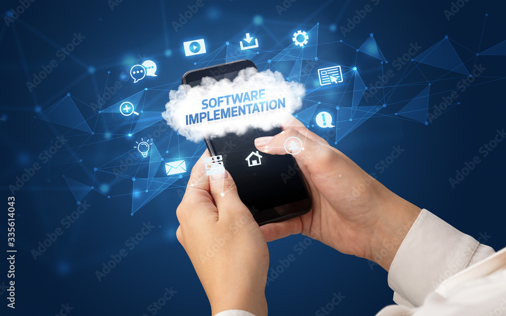 Female hand holding smartphone with SOFTWARE IMPLEMENTATION inscription, cloud technology concept Female hand holding smartphone with SOFTWARE IMPLEMENTATION inscription, cloud technology concept