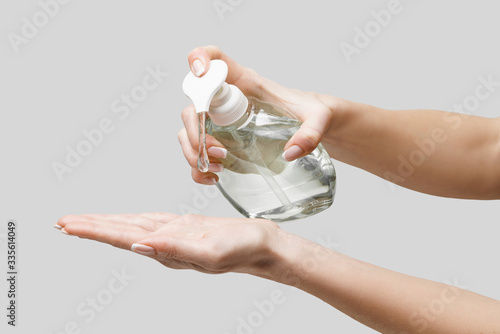 Obraz na plátne Female hands using hand sanitizer gel or liquid soap dispenser over light grey b
