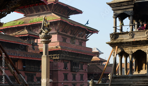 Statue of Malla King on top af o column, amongst Patan Durbar square temples in Kathmandu, Nepal
