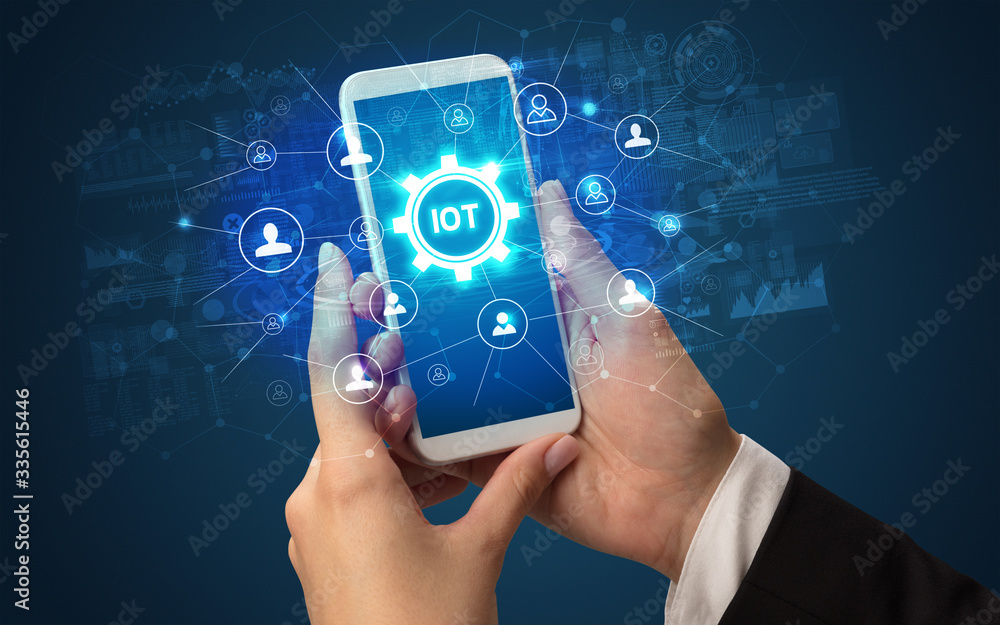 Female hand holding smartphone with IOT abbreviation, modern technology concept Female hand holding smartphone with IOT abbreviation, modern technology concept