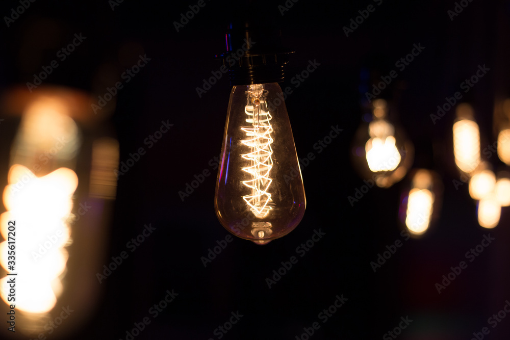 Edison lamp with warm light sways lightly on a black background