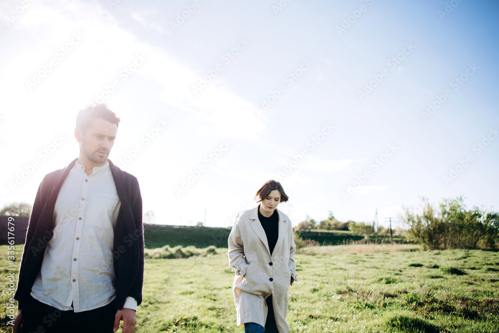 Loving hipster couple walking in the field, kissing and holding hands, hugging, lying in the grass in the spring at sunset. Photo with lens flare Loving hipster couple walking in the field, kissing and holding hands, hugging, lying in the grass in the spring at sunset. Photo with lens flare