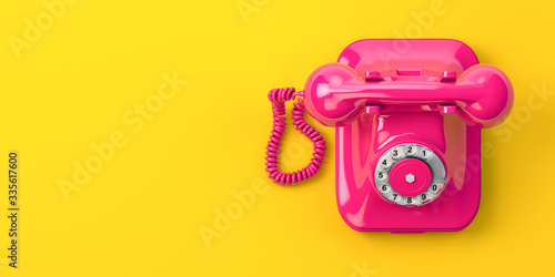 Vintage pink telephone on yellow background.