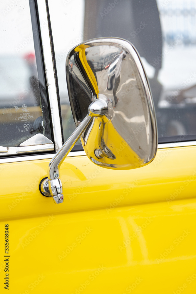 Chrome mirror of an old yellow car