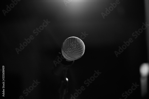 The microphone for the stage stands on a stand on a black background. Black and whire photography.
