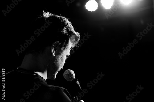 Young handsome guy emotionally sings and speaks into the microphone. Black and white photography