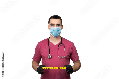 A doctor in a surgical mask holds the sign 