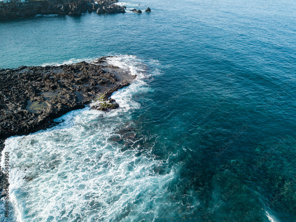 waves are breaking on the rocks aerial view