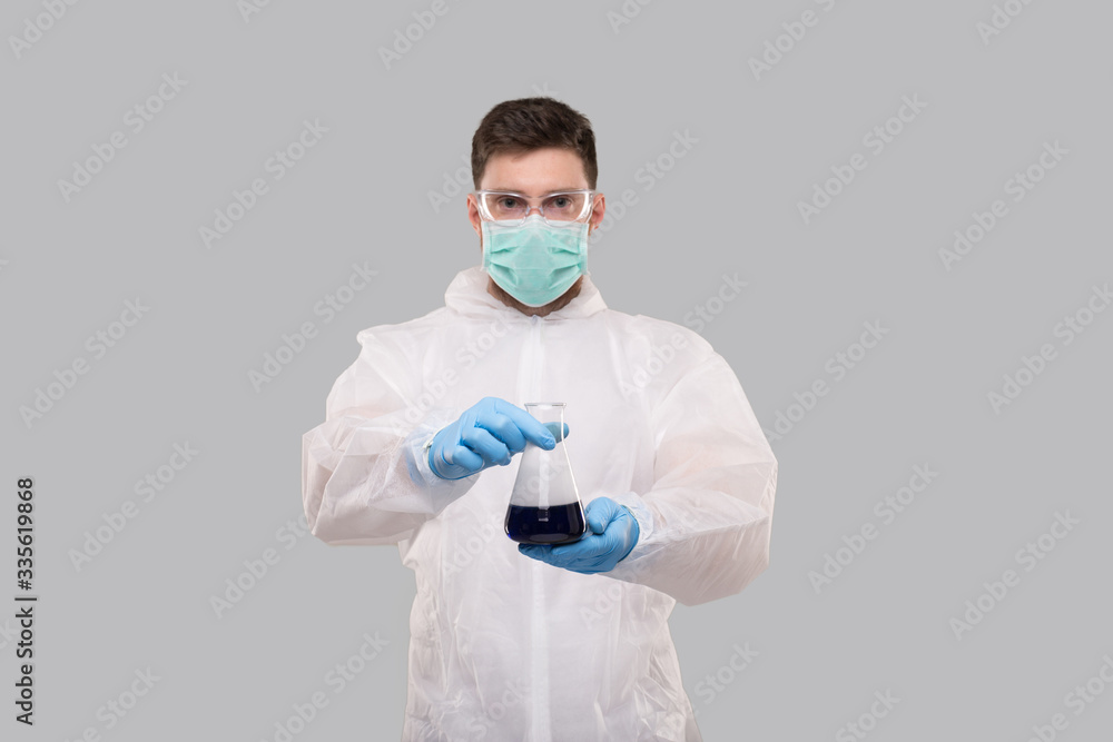 Male Laboratory Worker in Chemical Suit, Wearing Medical Mask and Glasses Showing Flask with Colorfull Liquid. Science, Medical, Virus Concept