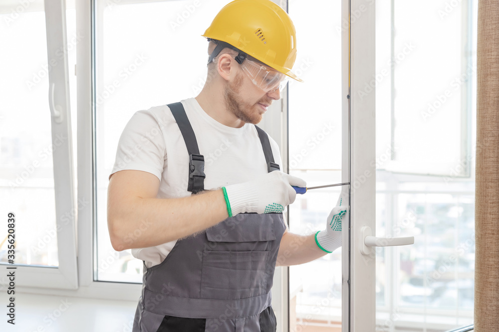 Worker man installs plastic windows white lock and seal adjustment Worker man installs plastic windows white lock and seal adjustment