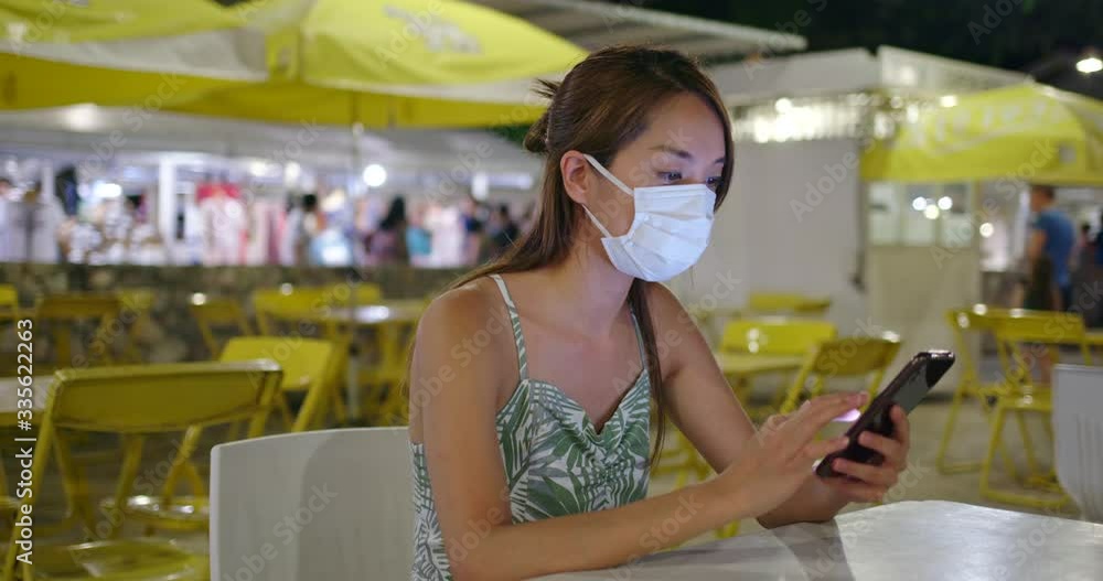 Woman wear medical face mask and use of mobile phone at outdoor restaurant Woman wear medical face mask and use of mobile phone at outdoor restaurant