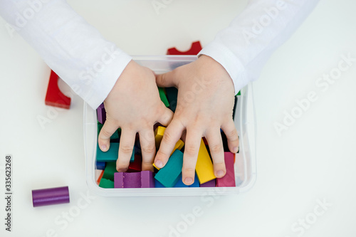 The child stereotypically plays with colored blocks of a wooden constructor. Concept of autism diagnosis and child development. Close. photo