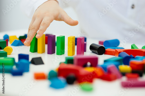 Building items in a single row. Concept of diagnostics of children's autism. A child plays with a colored wooden construction tool.