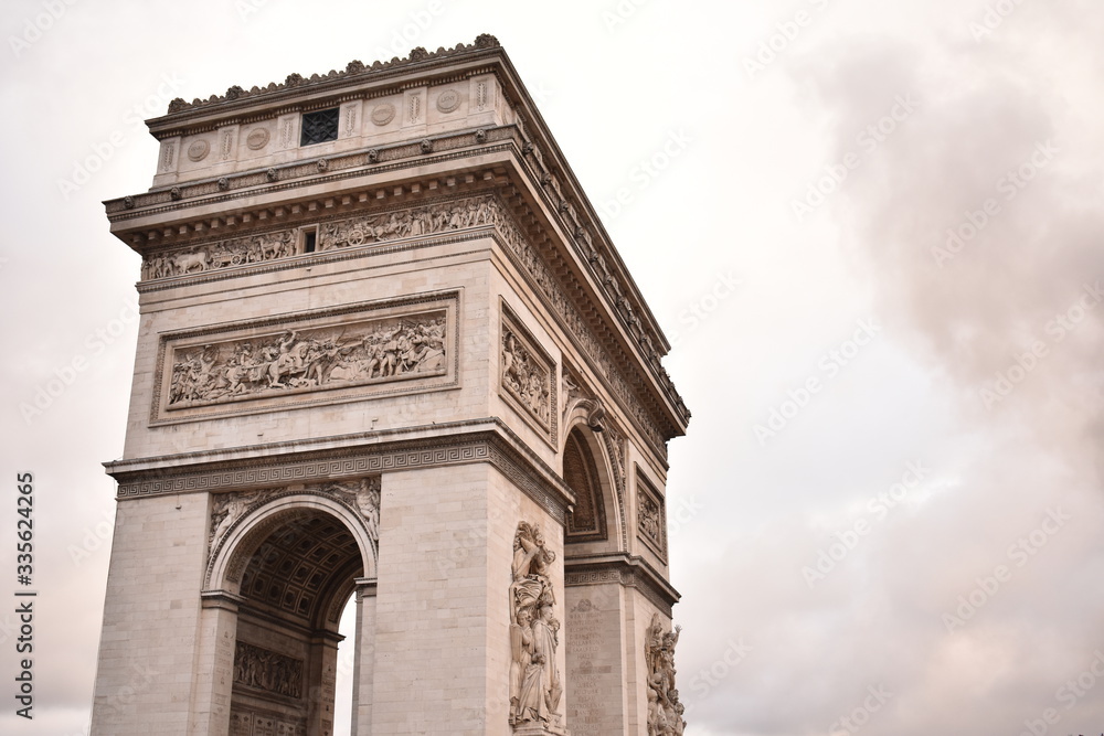 Arc de Triomphe with smoke in the background on an overcast day in Paris France