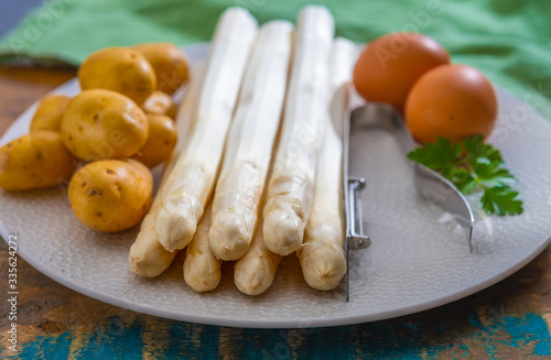 Ingredients for spring vegetarian dinner, high quality Dutch white asparagus, washed and peeled on board, ready to cookand, young potatoes and eggs photo