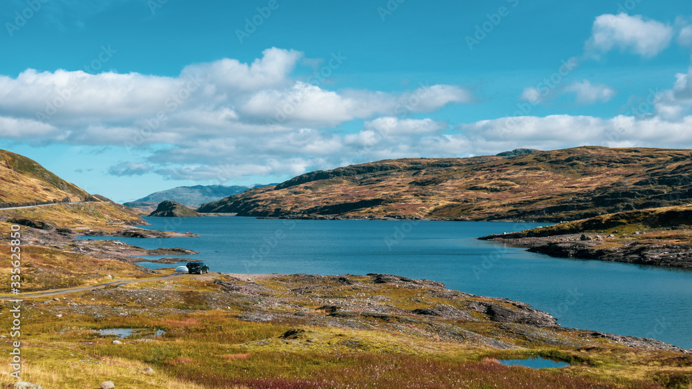 Norway high mountains lake recreation on sunny day color graded landscape. Wild nature travel, blue sky, bright colors. Hiking scandinavian scenery Norway high mountains lake recreation on sunny day color graded landscape. Wild nature travel, blue sky, bright colors. Hiking scandinavian scenery