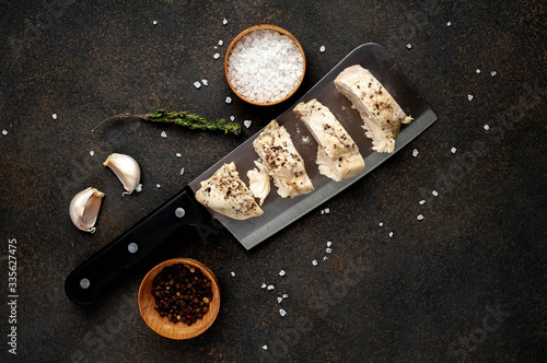 chicken breast on a knife with spices on a stone background with copy space for your text.