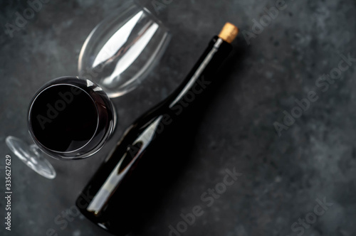 Bottle of red wine and glasses with wine on a stone background. Top view with copy space.