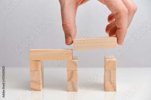 Business takeover concept. Hand holds wooden blocks on a white background.