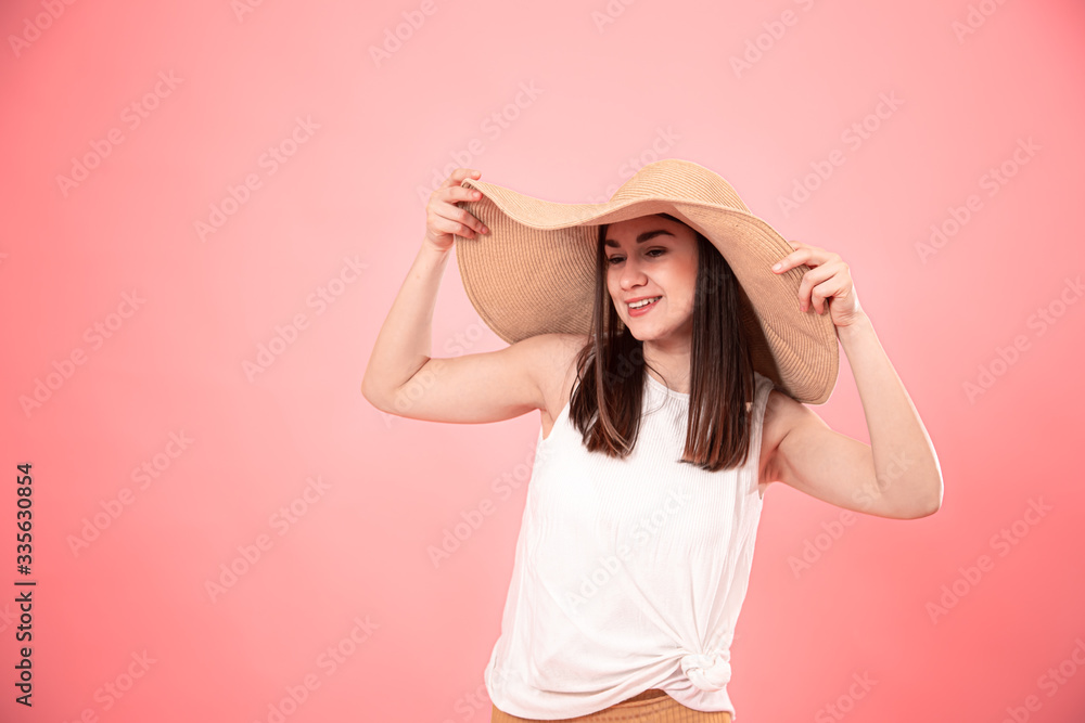 Portrait of a young woman in a large summer hat, on a pink background . Portrait of a young woman in a large summer hat, on a pink background .