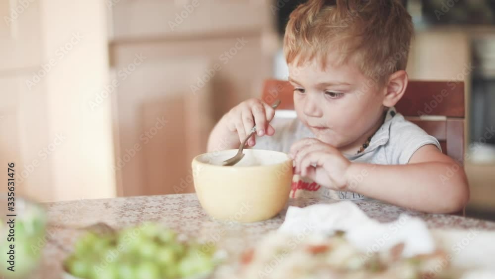 blond-haired boy eats soup in the kitchen
blond-haired boy eats soup in the kitchen