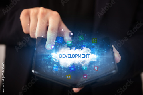 Businessman holding a foldable smartphone with DEVELOPMENT inscription, technology concept