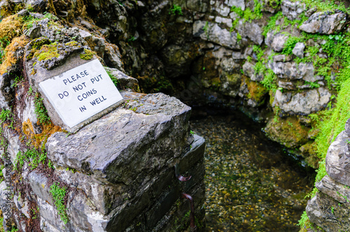 Sign asking pilgrims not to throw coins into a holy well