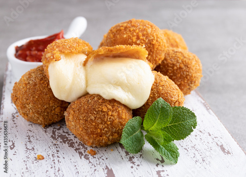 Fried breaded mozzarella cheese balls with tomato sauce close up