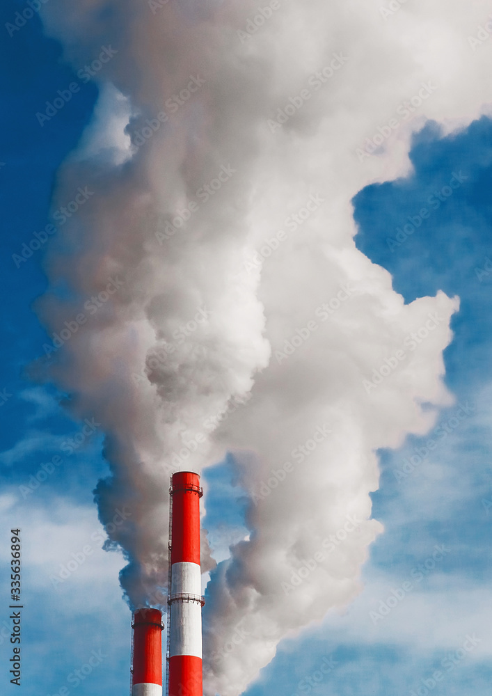 Environmental pollution, environmental problem, smoke from the chimney of an industrial plant or thermal power plant on a background of blue sky with clouds