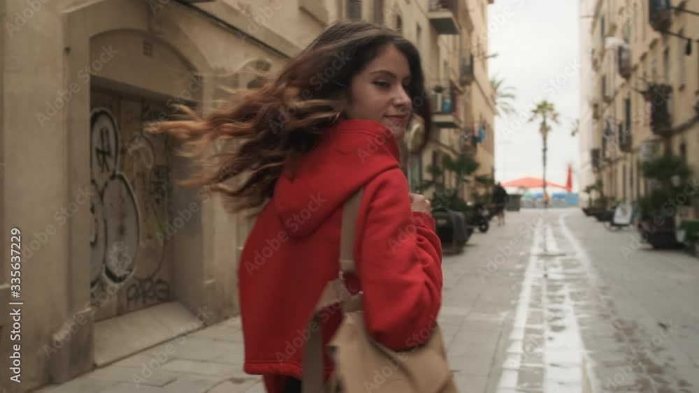Tracking around shot of pretty stylish hispanic girl with backpack happily walking through cozy street Tracking around shot of pretty stylish hispanic girl with backpack happily walking through cozy street