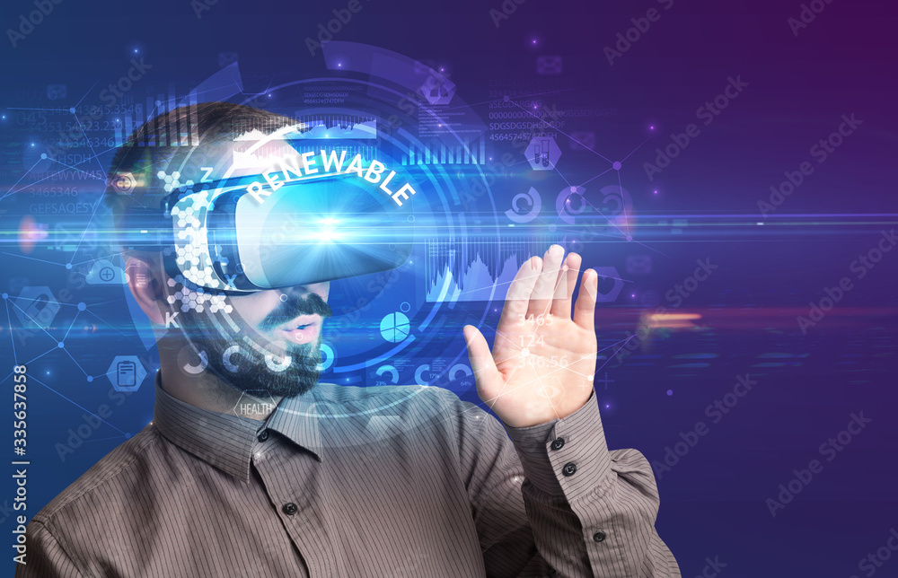 Businessman looking through Virtual Reality glasses with RENEWABLE inscription, innovative technology concept Businessman looking through Virtual Reality glasses with RENEWABLE inscription, innovative technology concept