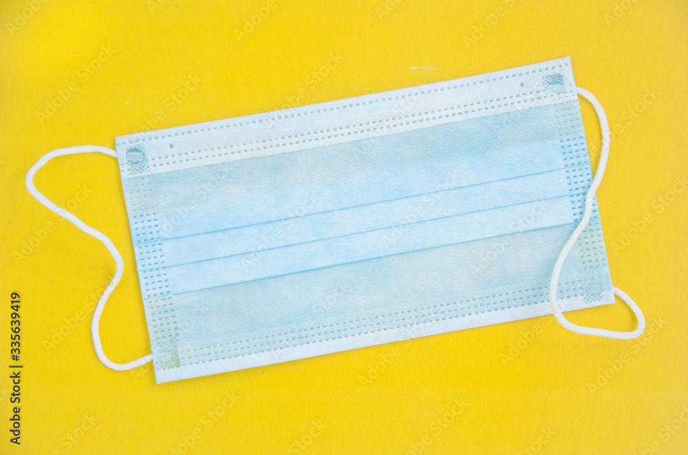 Medical surgical mask on a yellow background. Flat lay Medical surgical mask on a yellow background. Flat lay