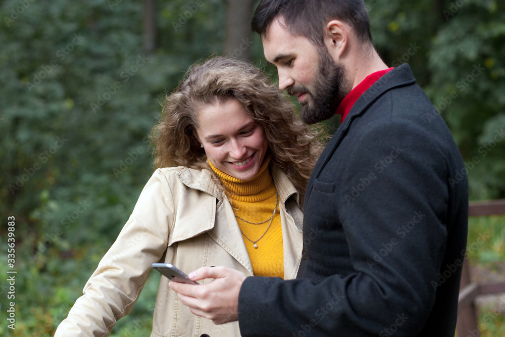 Young couple watch photos on smartphone in park Young couple watch photos on smartphone in park