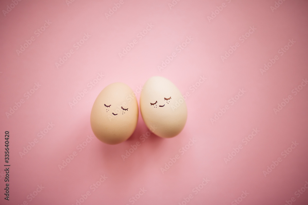 Two little easter eggs with a painted drawn happy faces on them in laying on the pink table isolated. Easter holidays decorations, preparations concept. Holy religious day. Copyspace, place for text. Two little easter eggs with a painted drawn happy faces on them in laying on the pink table isolated. Easter holidays decorations, preparations concept. Holy religious day. Copyspace, place for text.
