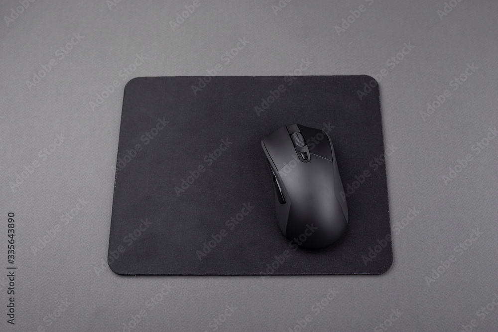 Wireless computer mouse in black on a gray background. Wireless computer mouse in black on a gray background.
