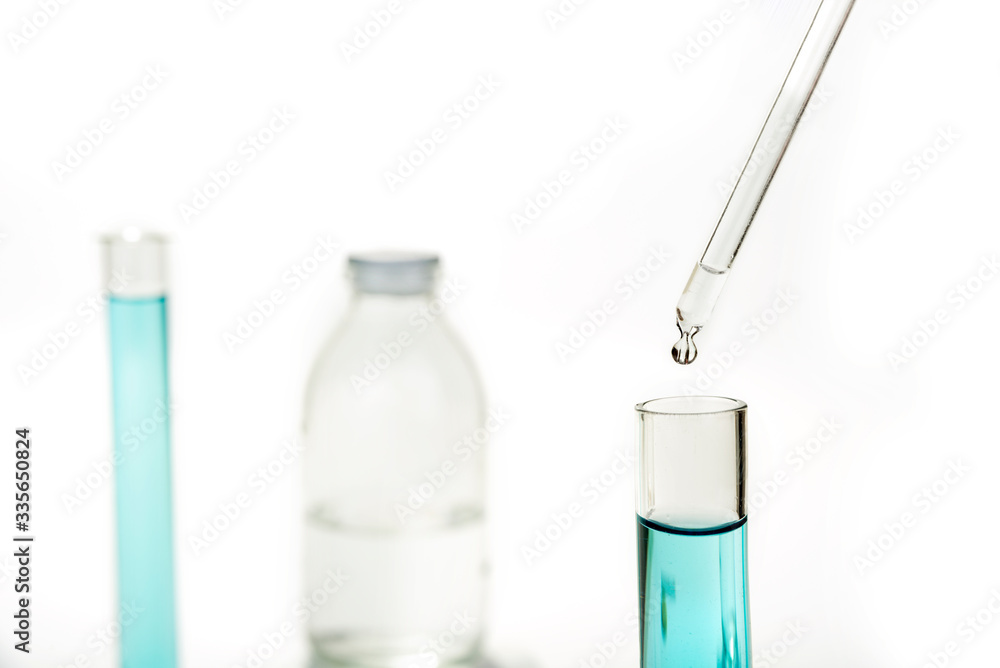 Dripping reagent into test tube with liquid sample Dripping reagent into test tube with liquid sample