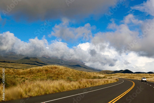 Hawaii Big Island nature background. Scenic landscape with highway 200 between Mauna Kea and Mauna Loa to Hilo. Bright blue sky with clouds over over mountain.