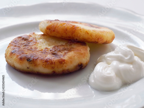 Cottage cheese pancakes are on a plate. Toasted cottage cheese pancakes with a Golden crust lie on a white plate