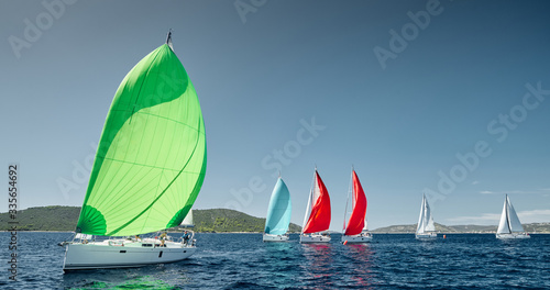 Foto Sailboats compete in a sail regatta at sunset, race of sailboats, reflection of