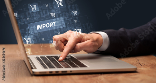 Businessman working on laptop with IMPORT inscription, online shopping concept