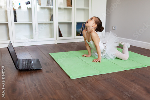 Pretty young ballerina practicing classic choreography during online class in ballet school, social distance during quarantine, self-isolation, online education concept photo