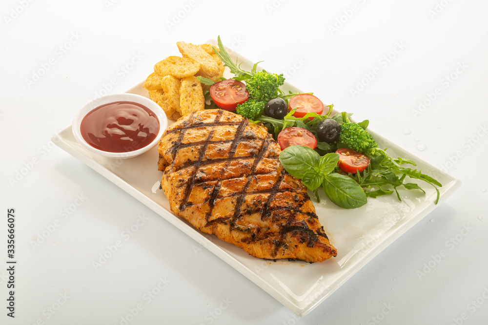 Italian style marinated chicken breast with fresh salads and tomato catchup on a white rectangle plate Italian style marinated chicken breast with fresh salads and tomato catchup on a white rectangle plate