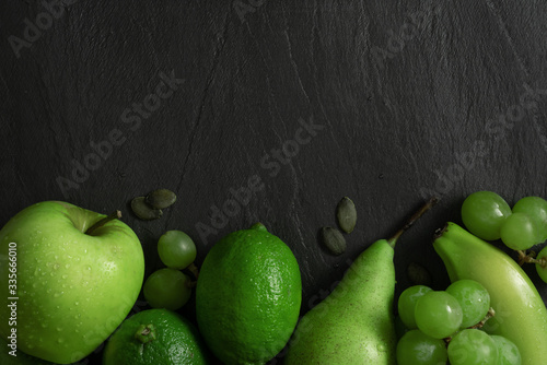 Flat lay top view. Summer abstract creative trendy fresh concept. Green fruits background. Dark stone slake plate with copy space.