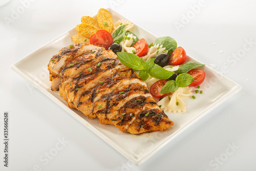 Italian style marinated chicken breast with fresh salads and tomato catchup on a white rectangle plate