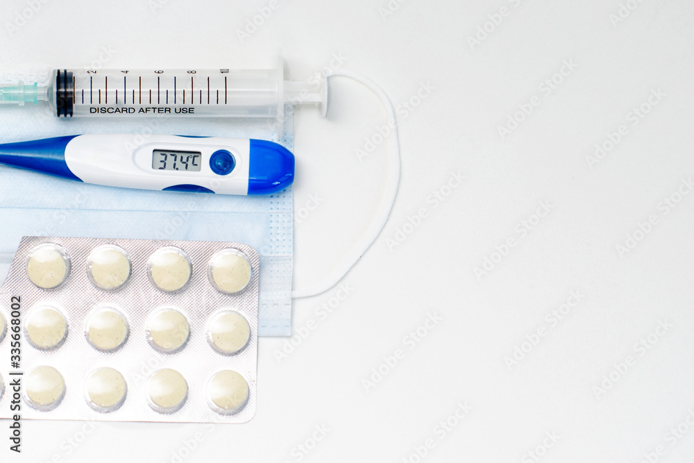 Obraz premium Facial protective mask, syringe, thermometer and pills. Flat lay and copy space concept. Pharmacy theme.