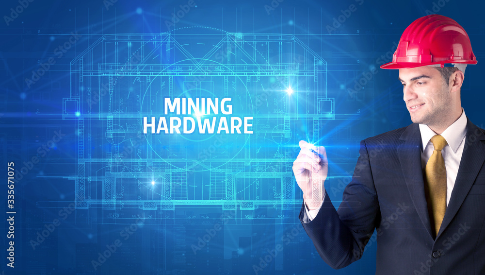 Handsome architect with helmet drawing MINING HARDWARE inscription, new technology concept Handsome architect with helmet drawing MINING HARDWARE inscription, new technology concept