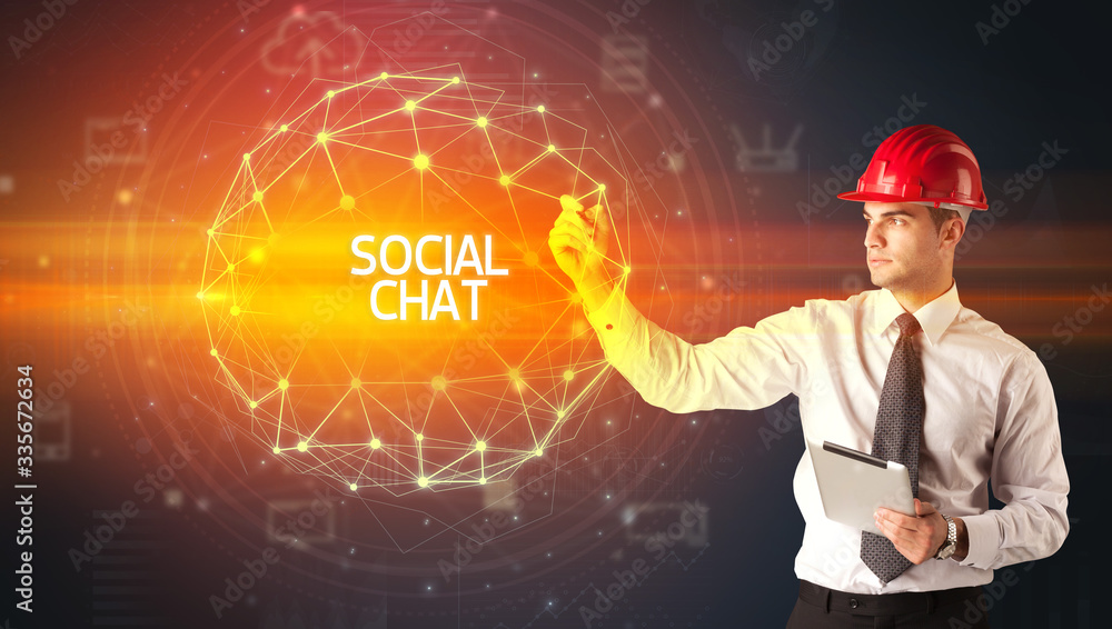 Handsome businessman with helmet drawing SOCIAL CHAT inscription, social construction concept Handsome businessman with helmet drawing SOCIAL CHAT inscription, social construction concept