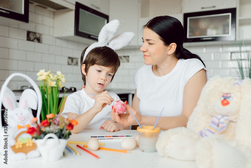Mother and her son painting Easter eggs. Happy family preparing for Easter day. Mother and her son painting Easter eggs. Happy family preparing for Easter day.